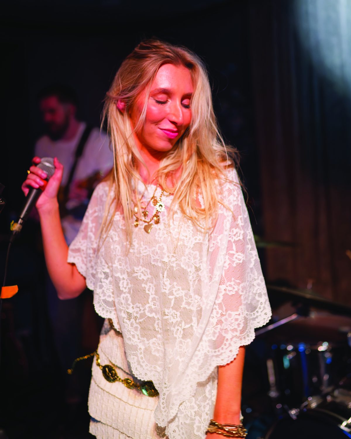 Sylvie smiling on stage in white lace