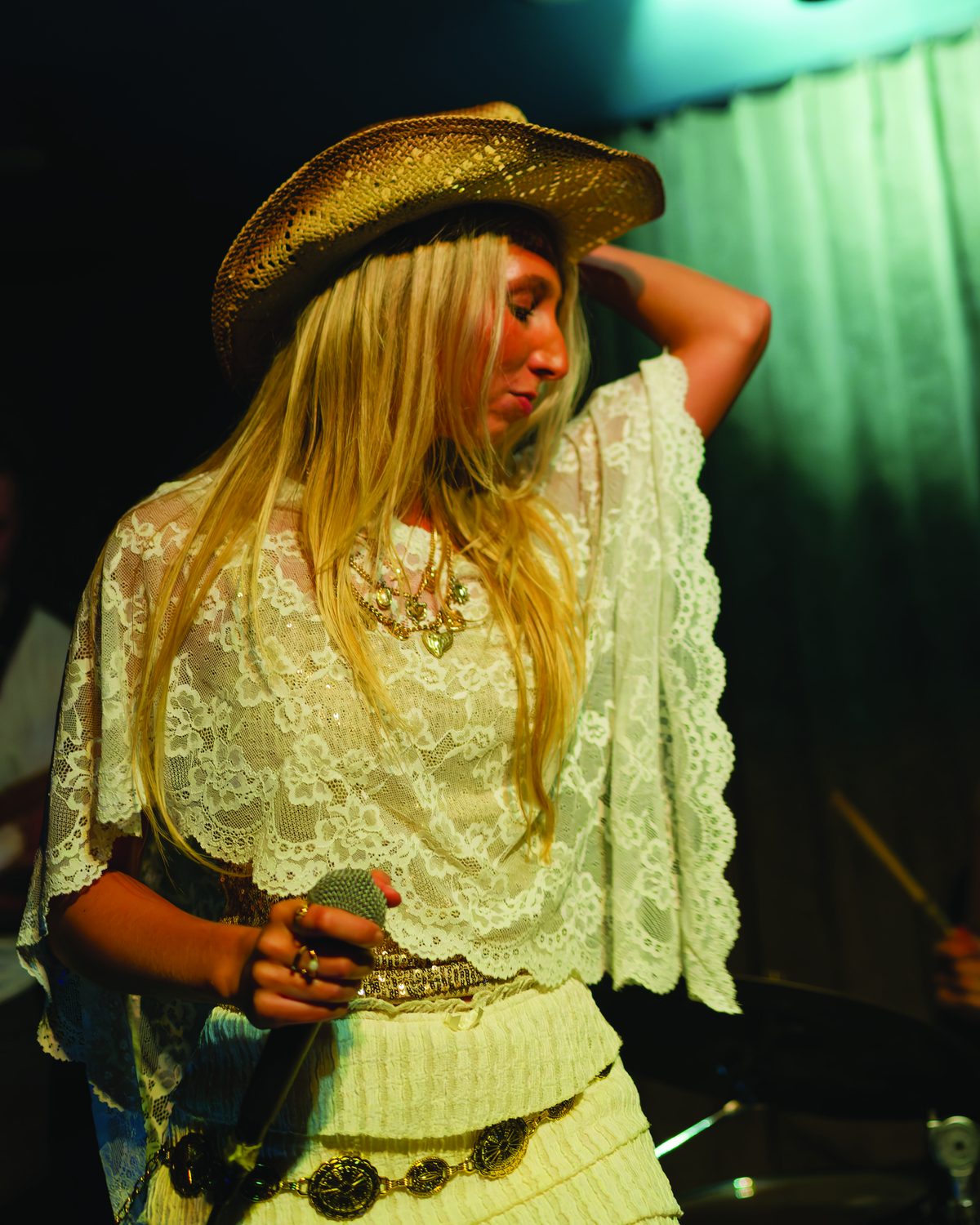 Sylvie in a cowboy hat on stage, holding the microphone